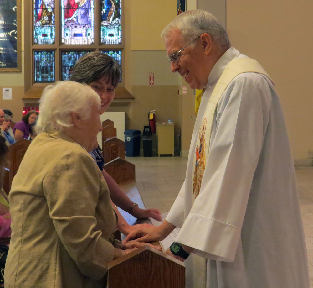 Father Steve Bossi, CSP, greets Paulist Associates Molly Suitkaitis (left) and Heather McClory before Mass.